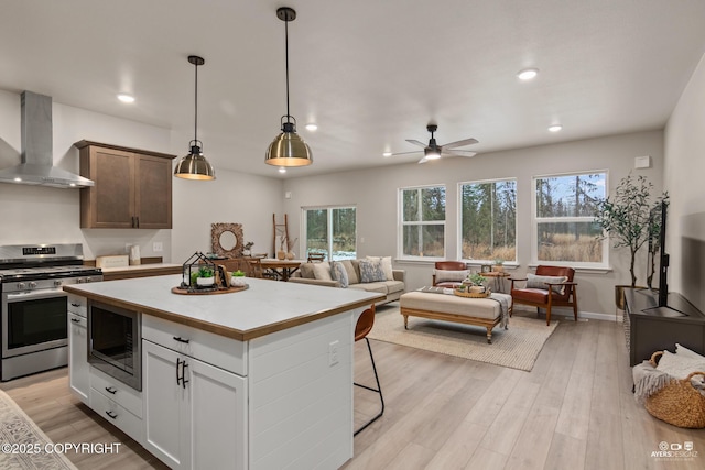 680 Wortham Ave, Kenai, AK 99611 - kitchen featuring wall chimney exhaust hood, stainless steel gas stove, black microwave, plenty of natural light, and recessed lighting