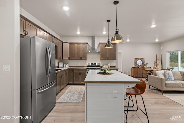 680 Wortham Ave, Kenai, AK 99611 - kitchen with appliances with stainless steel finishes, wall chimney exhaust hood, light wood finished floors, a center island, and recessed lighting