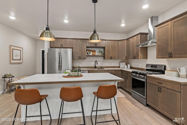 680 Wortham Ave, Kenai, AK 99611 - kitchen with appliances with stainless steel finishes, wall chimney exhaust hood, a sink, a breakfast bar, and light wood-style flooring
