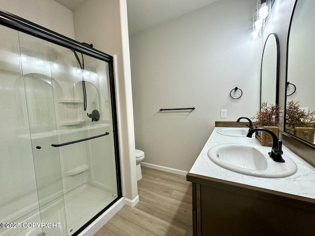 680 Wortham Ave, Kenai, AK 99611 - bathroom featuring wood finished floors, toilet, double vanity, a stall shower, and baseboards