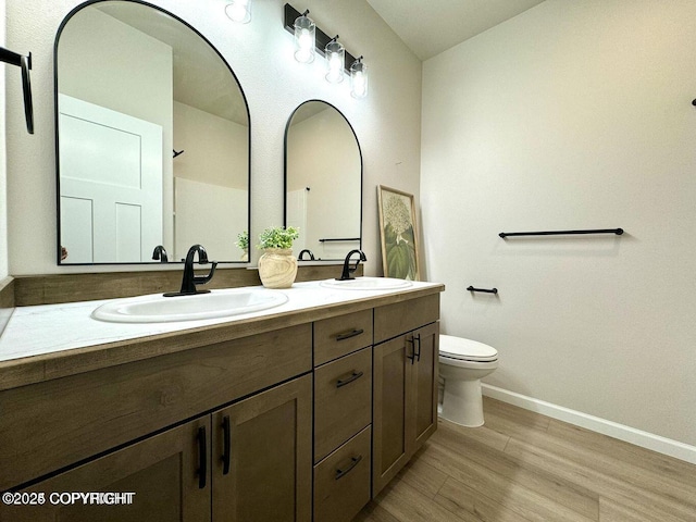 680 Wortham Ave, Kenai, AK 99611 - full bathroom featuring double vanity, baseboards, wood finished floors, and toilet