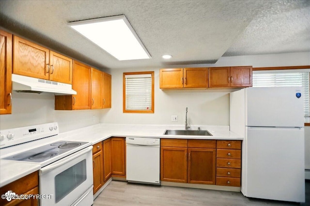 3962 Reka Dr # C1, Anchorage, AK 99508 - kitchen with white appliances, under cabinet range hood, a sink, light wood finished floors, and a textured ceiling