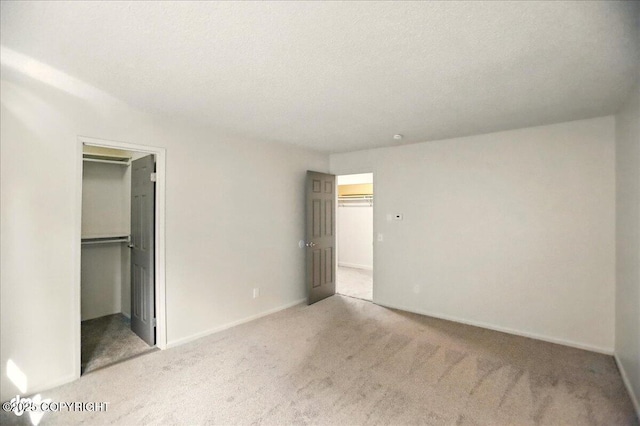 3962 Reka Dr # C1, Anchorage, AK 99508 - unfurnished bedroom with a walk in closet, carpet, a closet, baseboards, and a textured ceiling