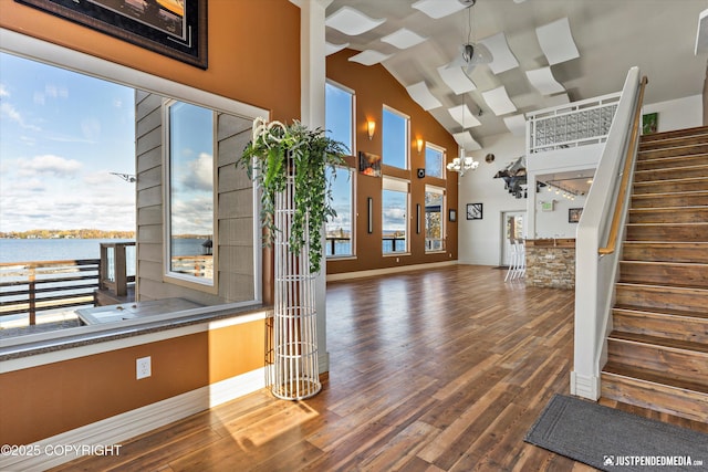 5322 S Big Lake Rd, Big Lake, AK 99652 - unfurnished living room with stairway, wood finished floors, high vaulted ceiling, and a water view