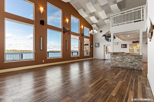 5322 S Big Lake Rd, Big Lake, AK 99652 - unfurnished living room featuring high vaulted ceiling, wood-type flooring, bar area, and a chandelier