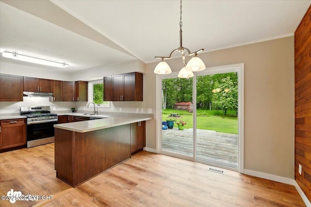 835 W Wilder Ave, Wasilla, AK 99654 - kitchen featuring stainless steel gas range, under cabinet range hood, a peninsula, light countertops, and light wood-style floors
