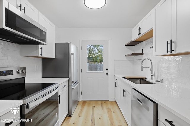 10108 Thimble Berry Dr, Anchorage, AK 99515 - kitchen featuring appliances with stainless steel finishes, a sink, light wood finished floors, open shelves, and white cabinets