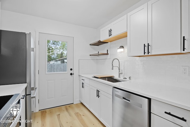 10108 Thimble Berry Dr, Anchorage, AK 99515 - kitchen featuring stainless steel appliances, a sink, light wood finished floors, tasteful backsplash, and white cabinets