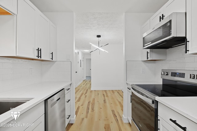 10108 Thimble Berry Dr, Anchorage, AK 99515 - kitchen with appliances with stainless steel finishes, white cabinets, light wood-type flooring, a textured ceiling, and tasteful backsplash