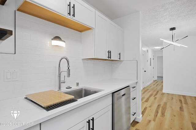 10108 Thimble Berry Dr, Anchorage, AK 99515 - kitchen with stainless steel dishwasher, a sink, decorative backsplash, white cabinets, and a textured ceiling