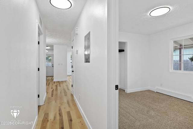 10108 Thimble Berry Dr, Anchorage, AK 99515 - hallway with a textured ceiling, baseboards, light wood-style flooring, and a baseboard radiator