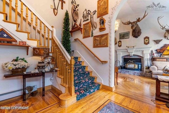 5411 Honeysuckle Ln, Wasilla, AK 99654 - stairs featuring wood-type flooring, arched walkways, a premium fireplace, and baseboards