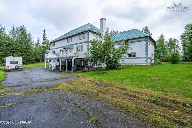 5411 Honeysuckle Ln, Wasilla, AK 99654 - back of house featuring a standing seam roof, a yard, metal roof, and a chimney
