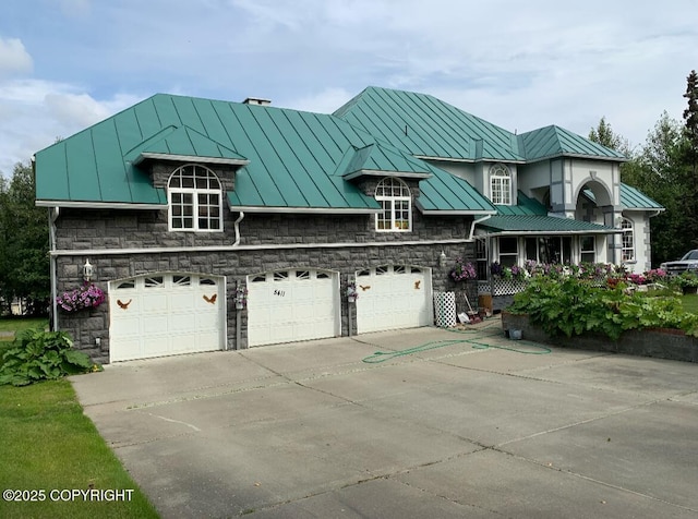 5411 Honeysuckle Ln, Wasilla, AK 99654 - view of front of house with a standing seam roof, concrete driveway, metal roof, stone siding, and an attached garage
