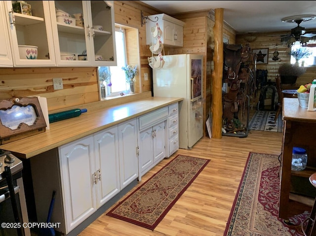 5411 Honeysuckle Ln, Wasilla, AK 99654 - kitchen featuring freestanding refrigerator, light wood-style floors, white cabinets, light countertops, and wooden walls