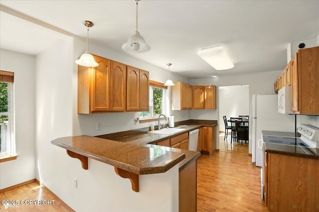 22030 Birch Creek Dr, Chugiak, AK 99567 - kitchen with a sink, a peninsula, light wood-type flooring, a kitchen breakfast bar, and white appliances