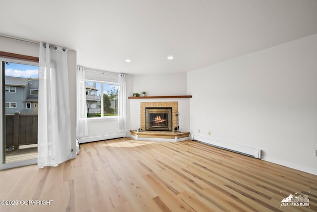 4109 Lynn Dr # 121, Anchorage, AK 99508 - unfurnished living room featuring a baseboard radiator, a baseboard heating unit, wood finished floors, a glass covered fireplace, and recessed lighting