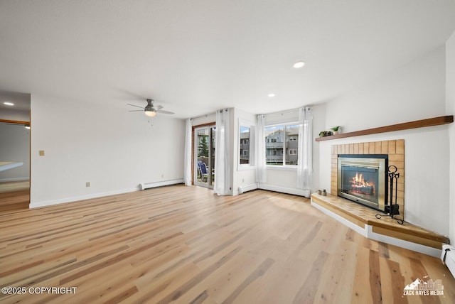 4109 Lynn Dr # 121, Anchorage, AK 99508 - unfurnished living room featuring baseboard heating, a baseboard heating unit, light wood finished floors, a ceiling fan, and a tile fireplace