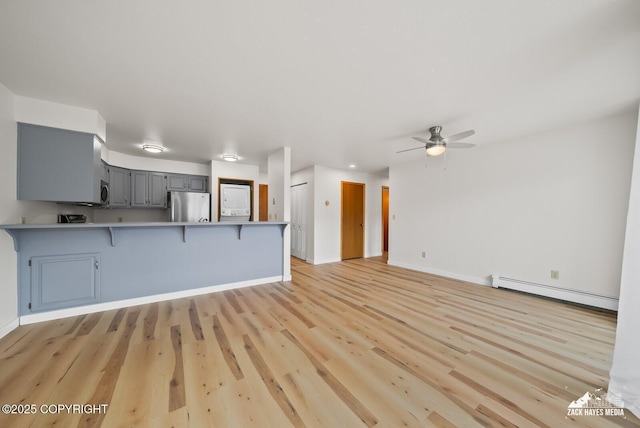 4109 Lynn Dr # 121, Anchorage, AK 99508 - kitchen with freestanding refrigerator, baseboard heating, a peninsula, a breakfast bar area, and gray cabinets