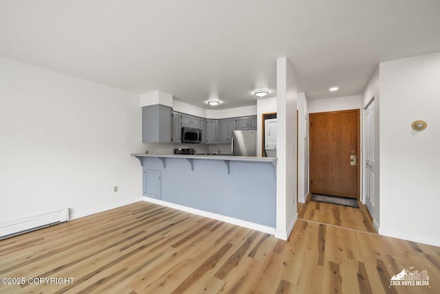 4109 Lynn Dr # 121, Anchorage, AK 99508 - kitchen featuring stainless steel appliances, gray cabinetry, a kitchen bar, light wood-style flooring, and light countertops