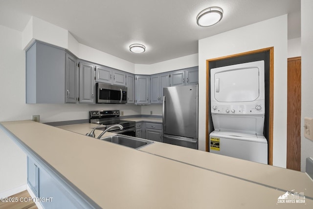 4109 Lynn Dr # 121, Anchorage, AK 99508 - kitchen featuring stainless steel appliances, estacked washer and dryer, gray cabinets, and light countertops