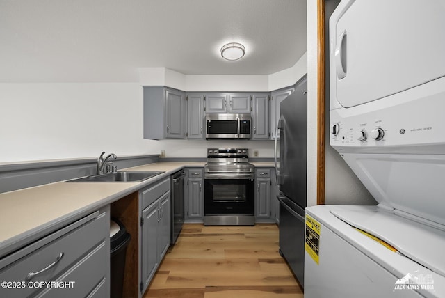 4109 Lynn Dr # 121, Anchorage, AK 99508 - kitchen with gray cabinetry, stainless steel appliances, estacked washer and dryer, and light wood-style floors