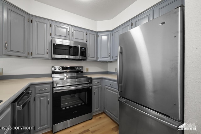 4109 Lynn Dr # 121, Anchorage, AK 99508 - kitchen featuring appliances with stainless steel finishes, gray cabinets, light wood finished floors, and light countertops