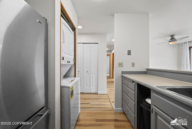 4109 Lynn Dr # 121, Anchorage, AK 99508 - kitchen with stacked washer / drying machine, light wood finished floors, gray cabinetry, ceiling fan, and light countertops