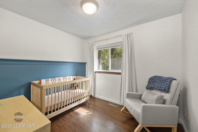 9845 E Lee Ann Dr, Palmer, AK 99645 - bedroom featuring wood finished floors, wainscoting, a nursery area, and a textured ceiling