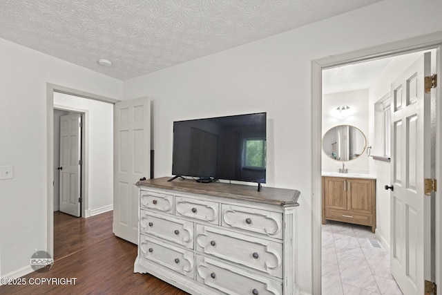 9845 E Lee Ann Dr, Palmer, AK 99645 - bedroom featuring baseboards, a sink, connected bathroom, and a textured ceiling