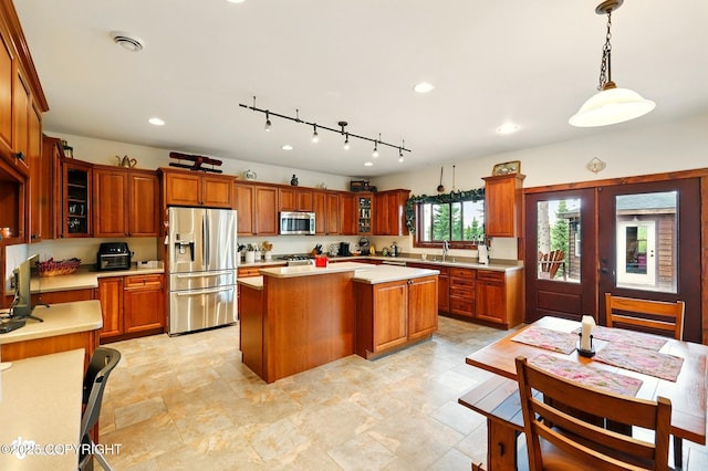 34952 Treeline Ave, Soldotna, AK 99669 - kitchen with stainless steel appliances, light countertops, a center island, brown cabinets, and glass insert cabinets