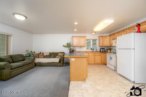 500 W Roy Rd, Wasilla, AK 99654 - kitchen with white appliances, light brown cabinets, open floor plan, under cabinet range hood, and a peninsula