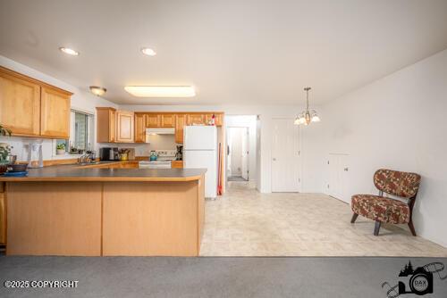 500 W Roy Rd, Wasilla, AK 99654 - kitchen featuring stove, freestanding refrigerator, a peninsula, ventilation hood, and hanging light fixtures