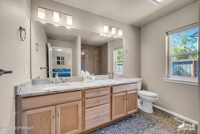 8620 Jade St, Anchorage, AK 99502 - bathroom featuring double vanity, a tile shower, connected bathroom, baseboards, and plenty of natural light