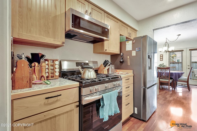 4139 Cosmos Dr, Anchorage, AK 99517 - kitchen with stainless steel appliances, light wood finished floors, light brown cabinets, light countertops, and a chandelier