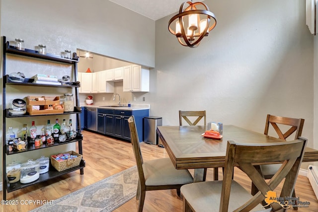 218 Deerfield Dr, Anchorage, AK 99515 - dining room with a chandelier, light wood-style flooring, a baseboard radiator, and a towering ceiling