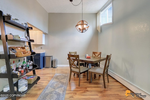218 Deerfield Dr, Anchorage, AK 99515 - dining space featuring baseboard heating, a chandelier, light wood finished floors, and baseboards