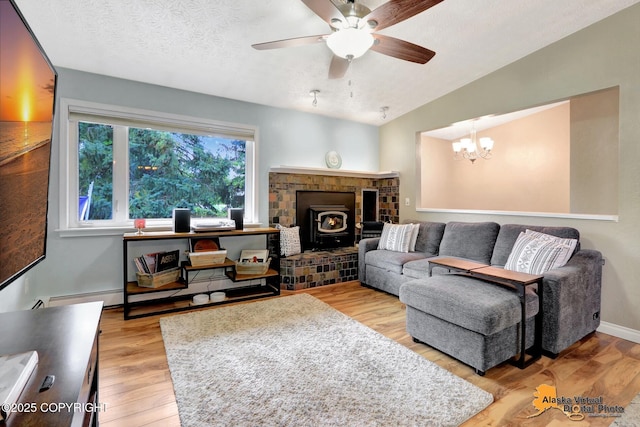 218 Deerfield Dr, Anchorage, AK 99515 - living area featuring a wood stove, ceiling fan, a chandelier, a textured ceiling, and light wood-type flooring