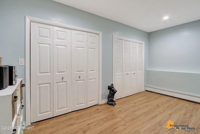 218 Deerfield Dr, Anchorage, AK 99515 - unfurnished bedroom featuring light wood-style floors, a baseboard heating unit, recessed lighting, and multiple closets