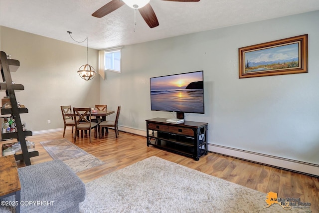 218 Deerfield Dr, Anchorage, AK 99515 - living room featuring a baseboard heating unit, wood finished floors, a ceiling fan, baseboards, and a textured ceiling