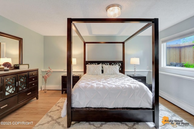 218 Deerfield Dr, Anchorage, AK 99515 - bedroom featuring baseboard heating, light wood-style flooring, and baseboards