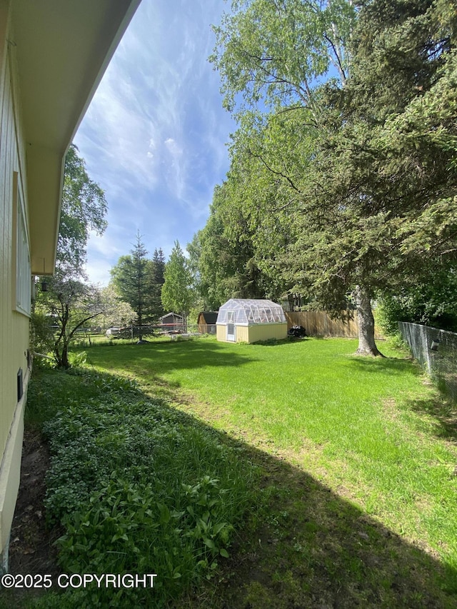 3316 Vassar Dr, Anchorage, AK 99508 - view of yard with an outdoor structure, a greenhouse, and view of wooded area