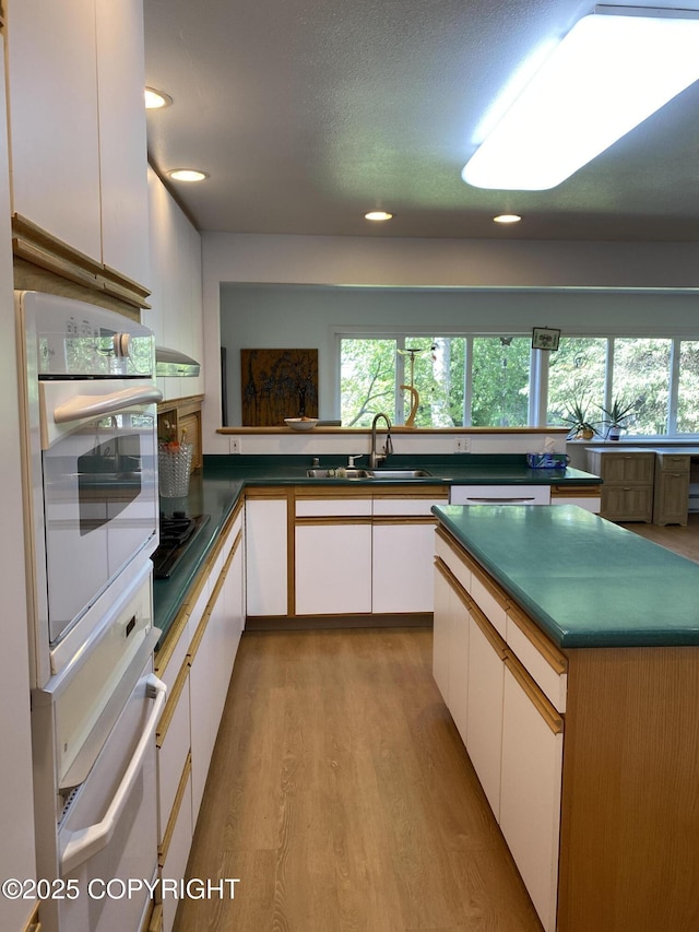 3316 Vassar Dr, Anchorage, AK 99508 - kitchen with a sink, light wood-style floors, white cabinetry, healthy amount of natural light, and recessed lighting