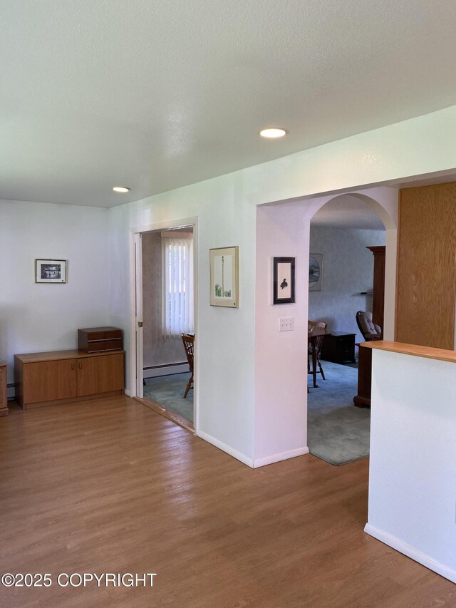 3316 Vassar Dr, Anchorage, AK 99508 - corridor with arched walkways, wood finished floors, a baseboard radiator, and baseboards