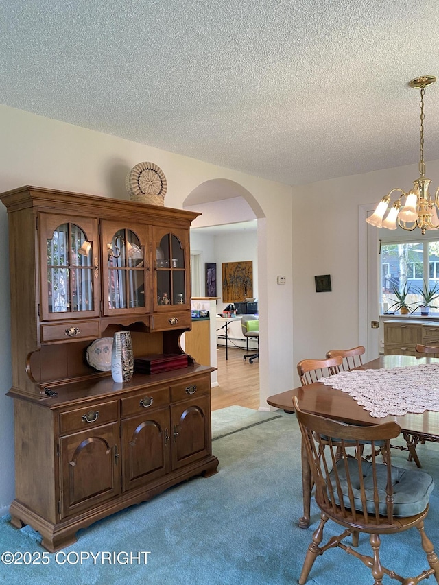 3316 Vassar Dr, Anchorage, AK 99508 - dining space featuring arched walkways, a chandelier, light carpet, and a textured ceiling