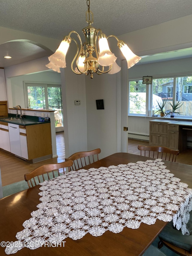 3316 Vassar Dr, Anchorage, AK 99508 - dining space featuring a baseboard heating unit, arched walkways, wood finished floors, a textured ceiling, and a chandelier
