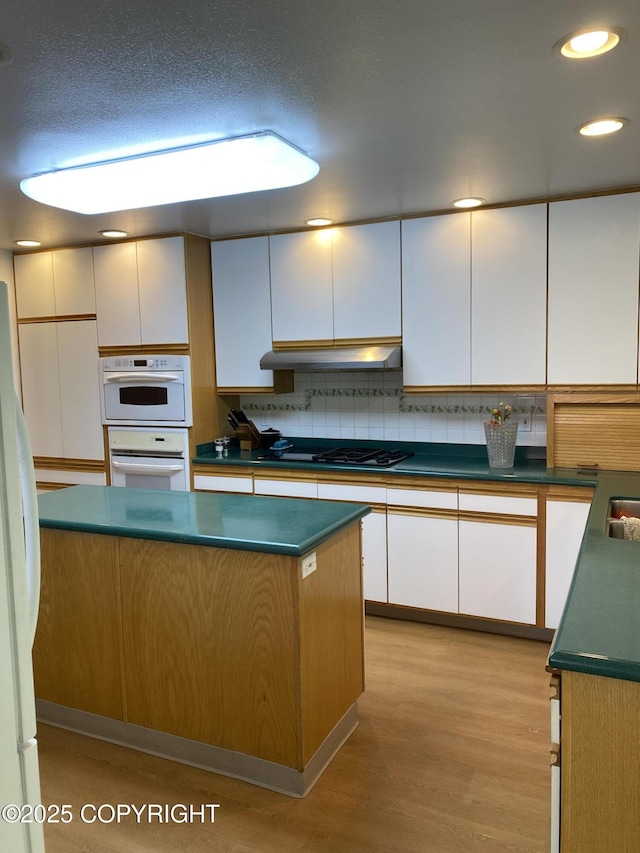 3316 Vassar Dr, Anchorage, AK 99508 - kitchen featuring white appliances, under cabinet range hood, white cabinets, light wood-style floors, and dark countertops