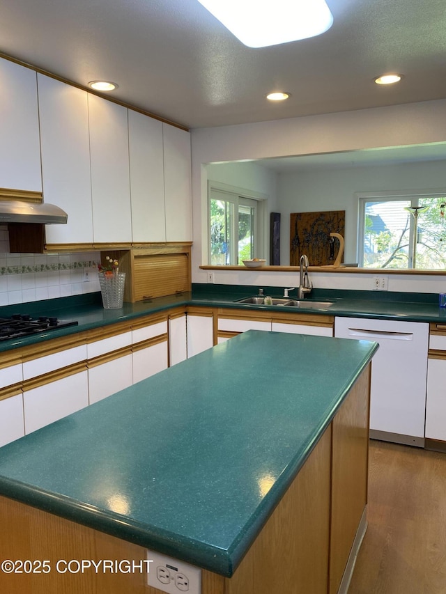 3316 Vassar Dr, Anchorage, AK 99508 - kitchen featuring dishwasher, under cabinet range hood, black stovetop, a sink, and wood finished floors