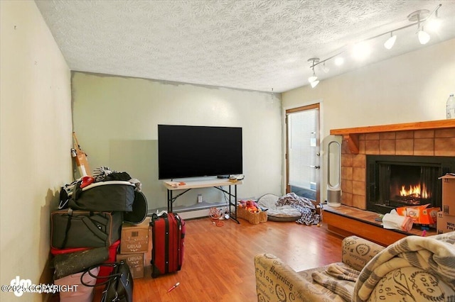 4510 Wright St # 25, Anchorage, AK 99507 - living area featuring wood finished floors, a tiled fireplace, a textured ceiling, and a baseboard heating unit