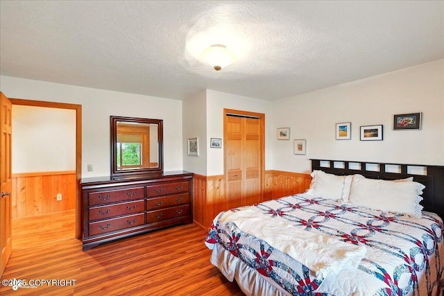 22325 Sterling Hwy, Ninilchik, AK 99639 - bedroom with wainscoting, wood walls, wood finished floors, a textured ceiling, and a closet